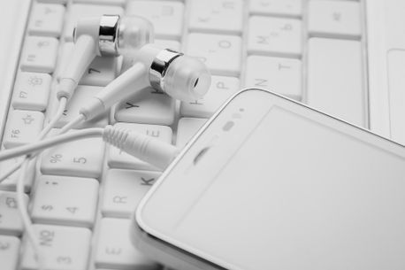 detalle movil blanco con auriculares sobre teclado